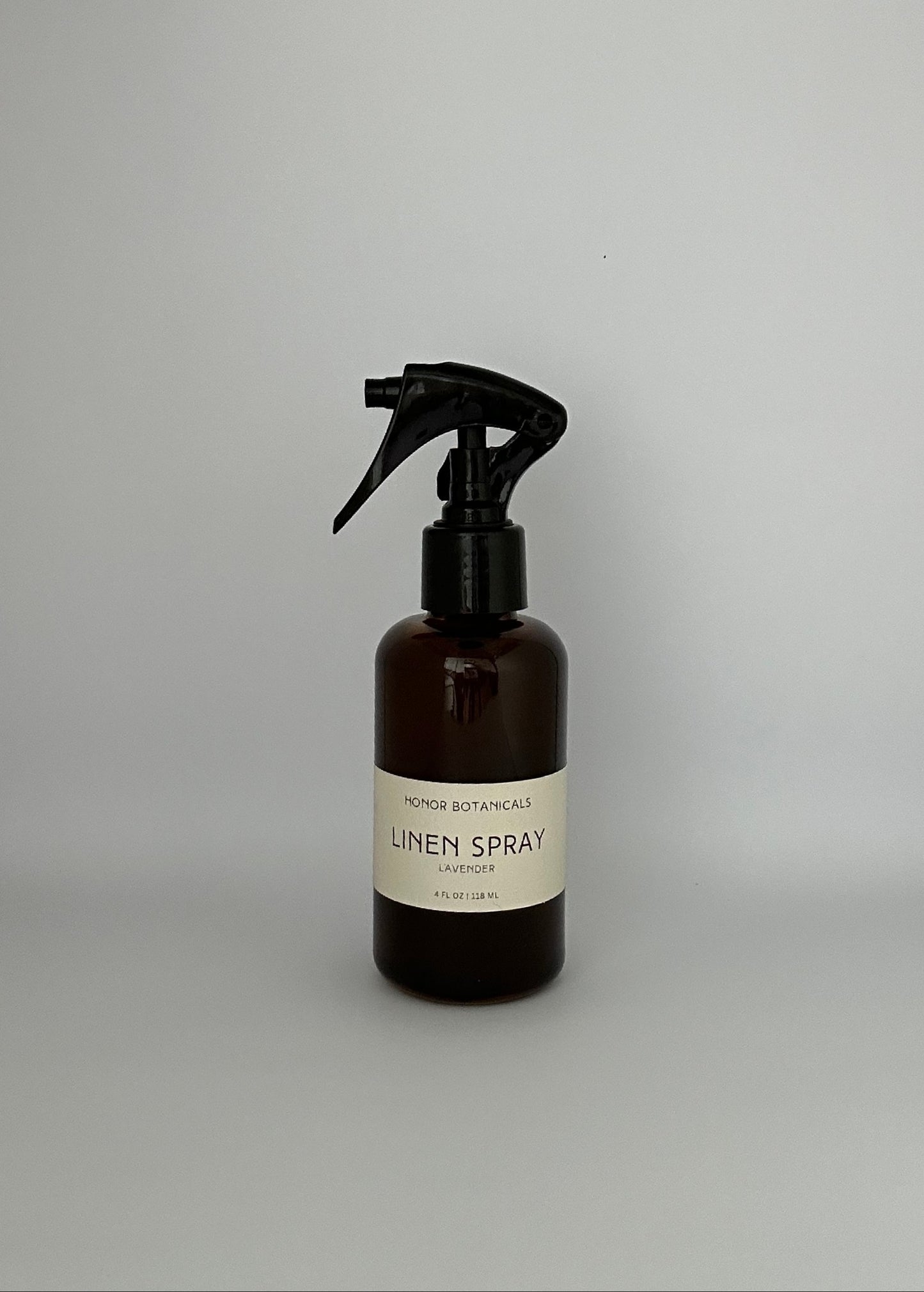 Dark brown glass lavender linen spray bottle with simple beige label.