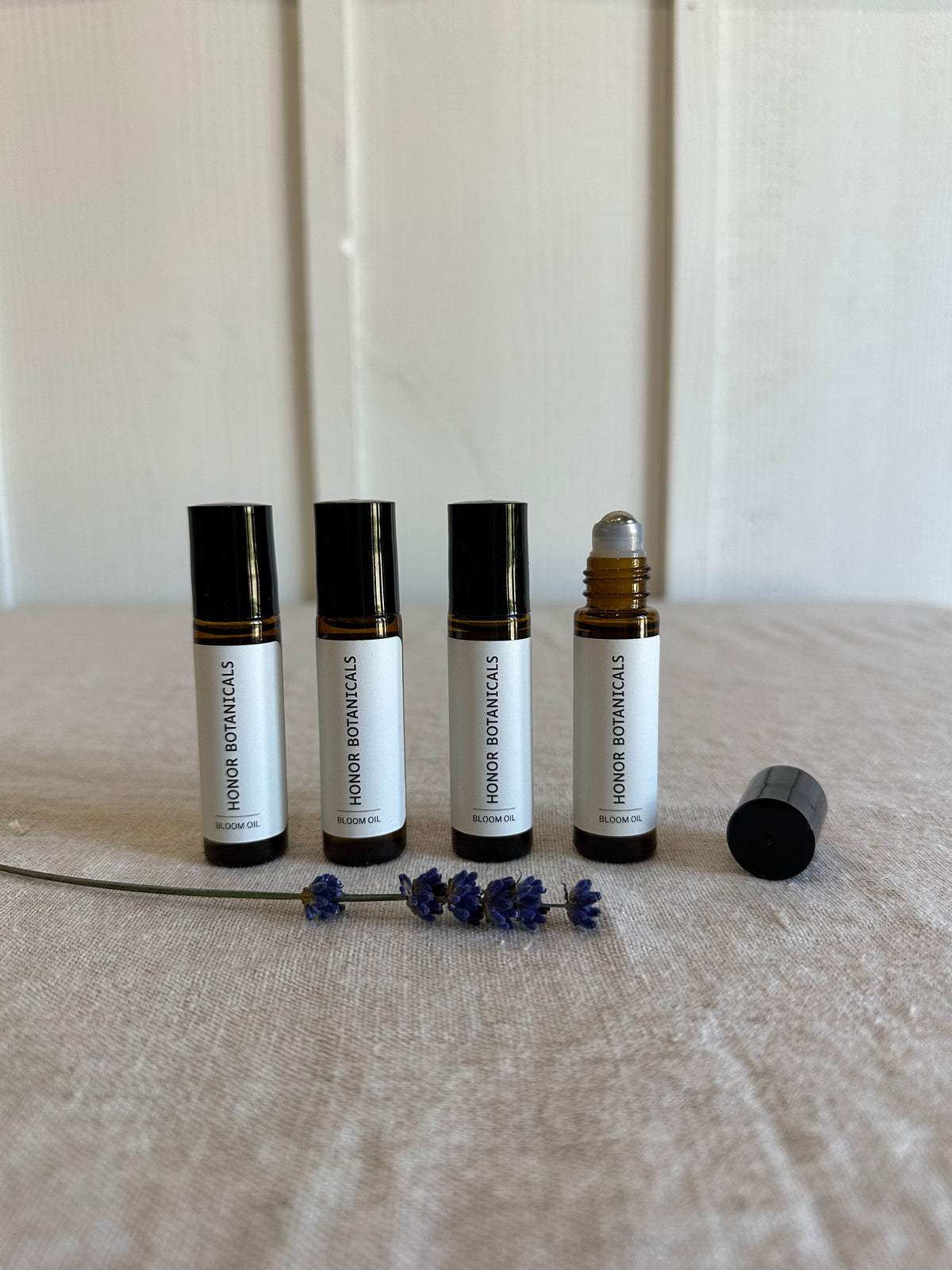 Five lavender roll-on bottles containing lavender essential oil and coconut oil on a textured surface.